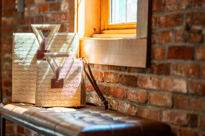 The Jane Tote and Mini in window light beside a brick wall