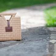 The Jane Tote Mini in raffia-embossed leather on a stone path