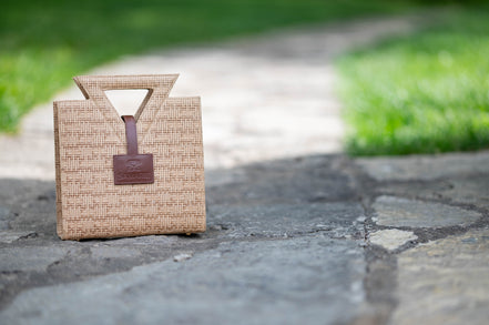 The Jane Tote Mini in raffia-embossed leather on a stone path